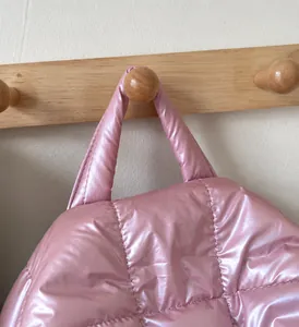 Detail of pink quilted puffer handbag handle with reinforced stitching on wooden hook