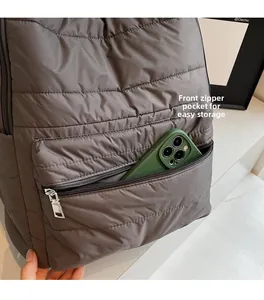 Detailed view of the front zipper pocket on a taupe quilted nylon backpack for easy storage