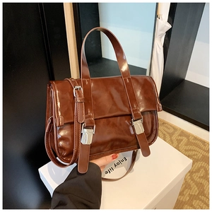 Detail of vintage brown oil wax leather messenger bag with polished buckles and top handle