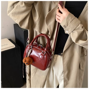 Detail of wine red glossy leather mini Boston bag with cute plush puppy charm accessory