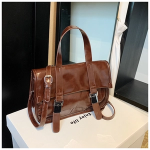 Close-up of vintage brown oil leather handbag with silver buckles and adjustable strap