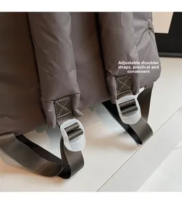Detail of adjustable padded shoulder strap with plastic buckle on taupe quilted backpack