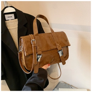 Detail view of the deep brown vintage satchel bag with silver metal buckles and top handle