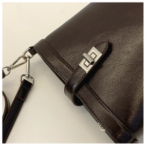 Detail of dark brown faux leather bucket bag with silver twist lock and polished finish