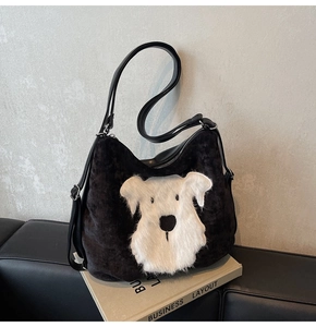 Détail d'un écusson chien en peluche sur un sac cabas en velours noir à anses en cuir