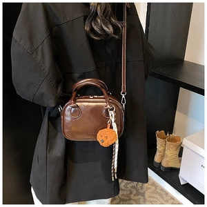 Detail of dark brown glossy PU leather mini square bag with cute teddy dog charm