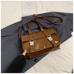 Detailed close-up of dark brown vintage satchel bag featuring silver metal buckle accents