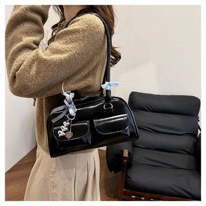 Detailansicht der glänzenden Lackleder-Schultertasche mit Bändern und Herzanhänger