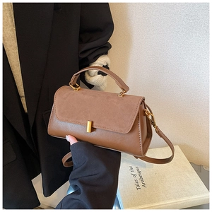 Détail d'un sac carré marron à deux textures avec boucle dorée et fine bandoulière