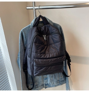 Details eines schwarzen gesteppten Rucksacks an einer Jeansjacke für einen lässigen Look