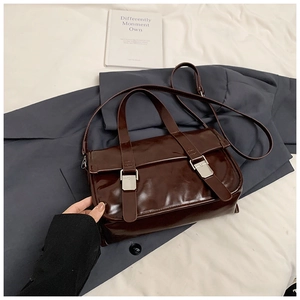 Detail of vintage dark brown faux leather bag with glossy finish and silver buckles