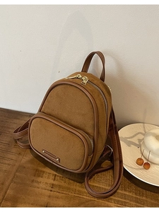 Mini sac à dos vintage en daim et cuir marron pour femme sur une table en bois