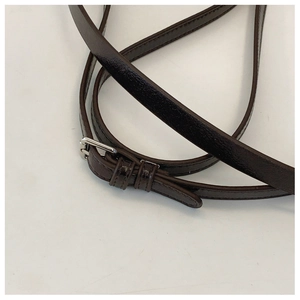Detail of dark brown patent leather strap with silver adjustable buckle on handbag