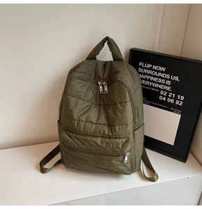 Detail eines armeegrünen Stepprucksacks mit zwei Reißverschlusstaschen und Seitentaschen
