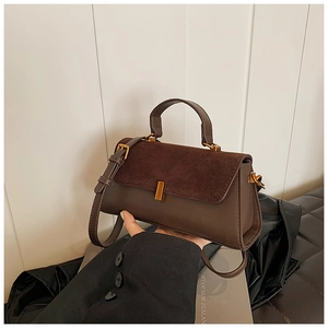 Détail d'un sac à main carré marron foncé montrant le daim mat et le cuir lisse