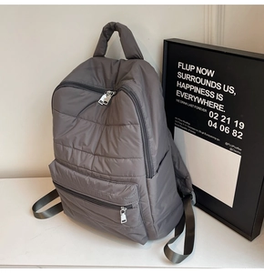 Seitenansicht des grauen gesteppten Puffer-Rucksacks aus Nylon mit Seitentaschen