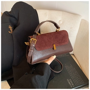 Détail du sac à main en cuir marron et daim bordeaux avec finitions en métal doré poli