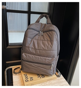 Nahaufnahme des grauen gesteppten Daunenrucksacks mit Front-Reißverschlusstasche und Textur