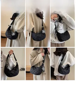 Dettaglio borsa hobo trapuntata nera con tracolla logata e ciondolo a fiore a scacchi