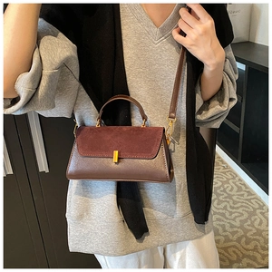 Detail of burgundy and brown patchwork square bag with gold buckle and shoulder strap