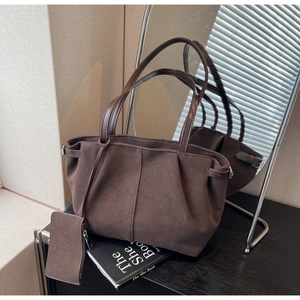 Detailaufnahme der kaffeebraunen Wildledertasche mit weicher Textur und Mini-Beutel