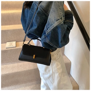 Détail du sac bandoulière noir avec rabat en daim et fermeture en métal doré élégante