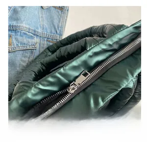 Detail van gladde metalen rits op gewatteerde donkergroene glanzende nylon draagtas