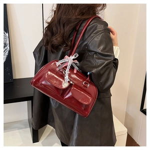 Detail der weinroten Lackledertasche mit Schleifenanhänger und Vordertaschen-Funktion