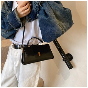Sac carré noir classique avec boucle dorée porté par un mannequin en veste en jean