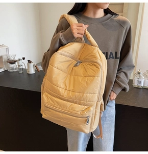 Detailansicht des khakifarbene gesteppte Rucksack mit horizontalen Nähten in einem gemütlichen Café