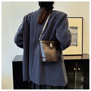 Rear view of model wearing a dark brown bucket bag with shiny silver glitter shoulder strap
