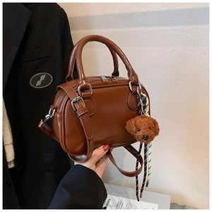 Brown PU leather crossbody pillow bag detail featuring a cute plush dog charm accessory