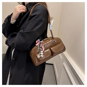 Detail einer braunen Lackleder-Schultertasche mit Herzanhängern und Schleifen-Details