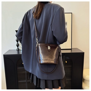 Close-up of a dark brown glossy leather bucket bag with silver buckle and thin strap