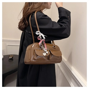 Detail der braunen glänzenden Bowlingtasche mit Vordertaschen und Spitzen-Anhängern