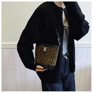 Detail of leopard print bucket bag with silver metal buckle on black leather strap