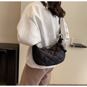 Dettaglio della borsa a mezzaluna in nylon nero trapuntato con ciondolo a cuore a scacchi
