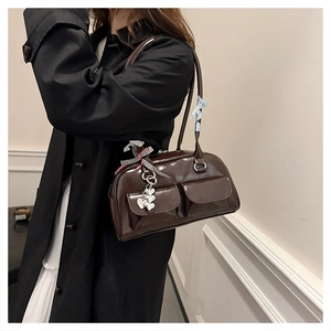 Detailaufnahme der dunkelbraunen Retro-Schultertasche aus Lackleder mit Anhängern