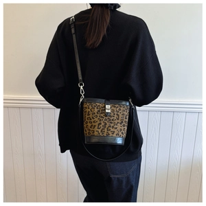 Rear view of a model wearing a leopard print bucket bag with black leather straps
