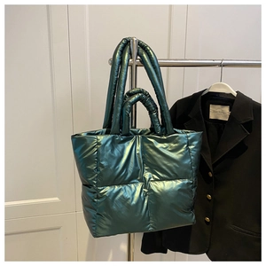 Detail of dark green quilted tote bag with metallic finish and multi-handle design