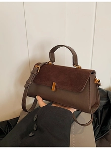 Sac à main marron en cuir et daim avec fermoir métallique doré porté par modèle