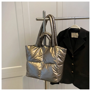 Detail of metallic gold quilted tote bag with long and short handles on a coat rack