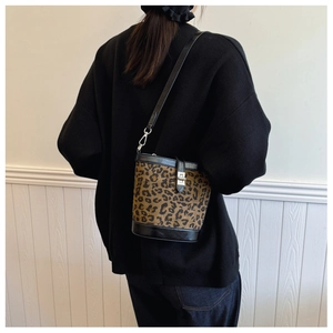 Detail of leopard print bucket bag with black leather trim and metal swivel clasp closure