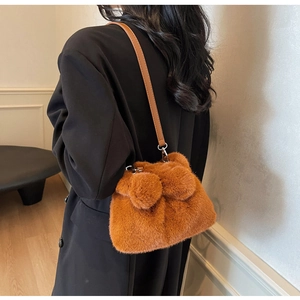 Detailsicht der braunen Plüsch-Beuteltasche mit Pelzkugeln und Leder-Schultergurt