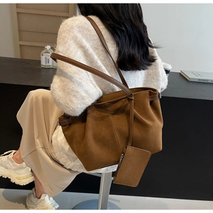 Braune Wildleder-Tragetasche am Modell mit minimalistischer Untertasche und geräumigem Design