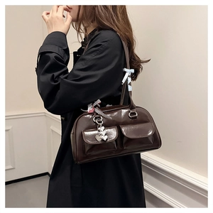 Detail einer braunen Lackleder-Bowlingtasche mit Seidentüchern und Herzanhänger