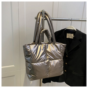Detailed close-up of metallic silver quilted tote bag with dual straps and puffer texture