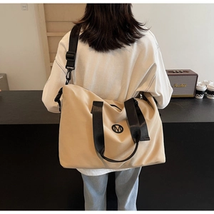 Detailed view of the large capacity beige travel bag with wide black shoulder straps