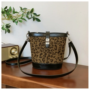 Detailed view of leopard print bucket bag with silver metal buckle on a rustic wood surface