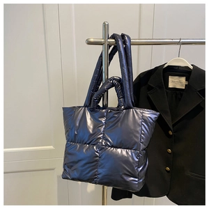 Detail of quilted glossy tote bag with dual handles and metallic navy blue finish
